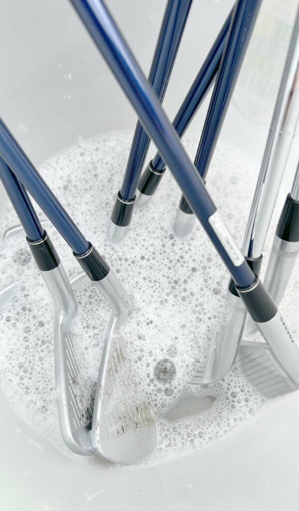 plonger têtes de clubs de golf dans l'eau savonneuse pour les nettoyer